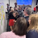 Room full of people working together on a topic using post it notes.